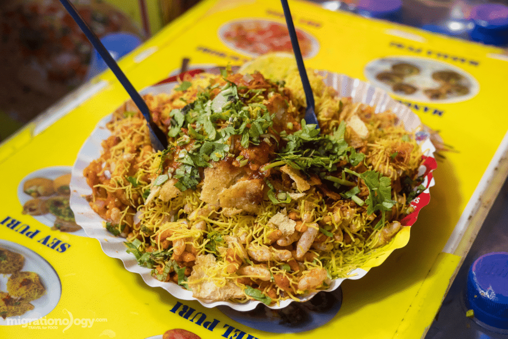 Bhelpuri served in a paper cone at Juhu Beach with puffed rice, sev, and chutney